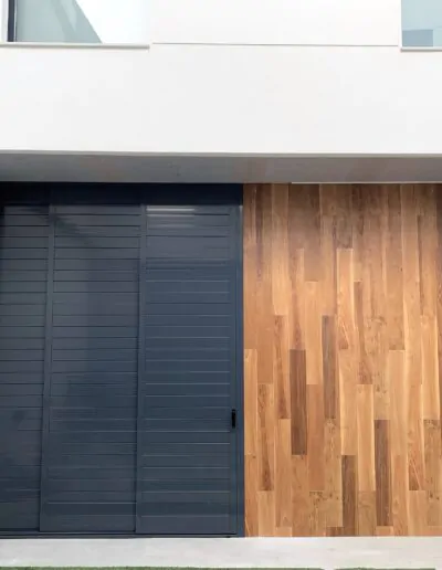 Puerta moderna de exterior con acabado en madera a la derecha