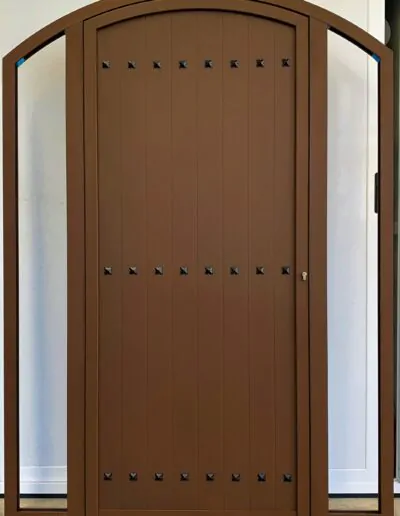 Puerta con forma de arco abatible en acabado marron y cristaleras enn los dos lados
