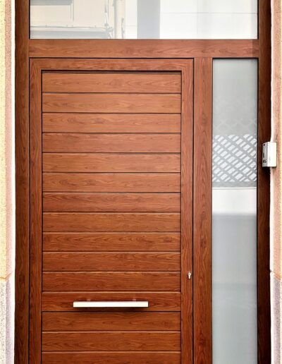 Diseño de puerta en acabado de madera exterior con ventanal pequeño en la derecha