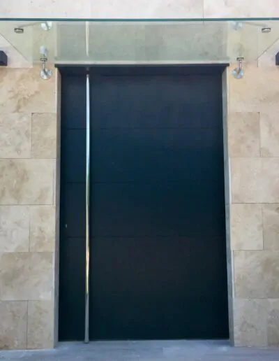 Puerta acabada en gris oscuro con un cristal arriba de la puerta