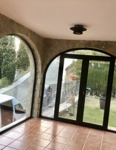 Ventanal de arco con acción abatible y acabado en negro con puerta abatible integrada