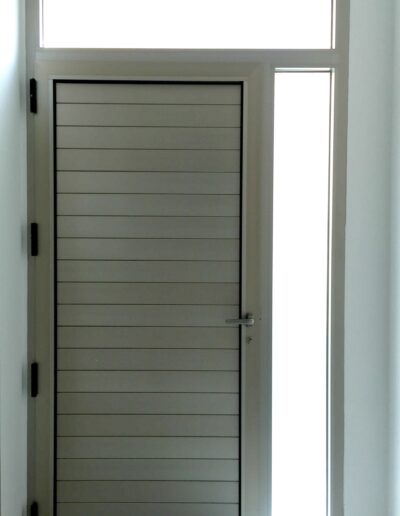 Diseño de puerta exterior con ventanal pequeño en la derecha y arriba ventanal rectangular