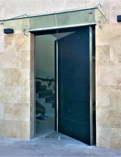 Puerta acabada en gris oscuro con un cristal arriba de la puerta